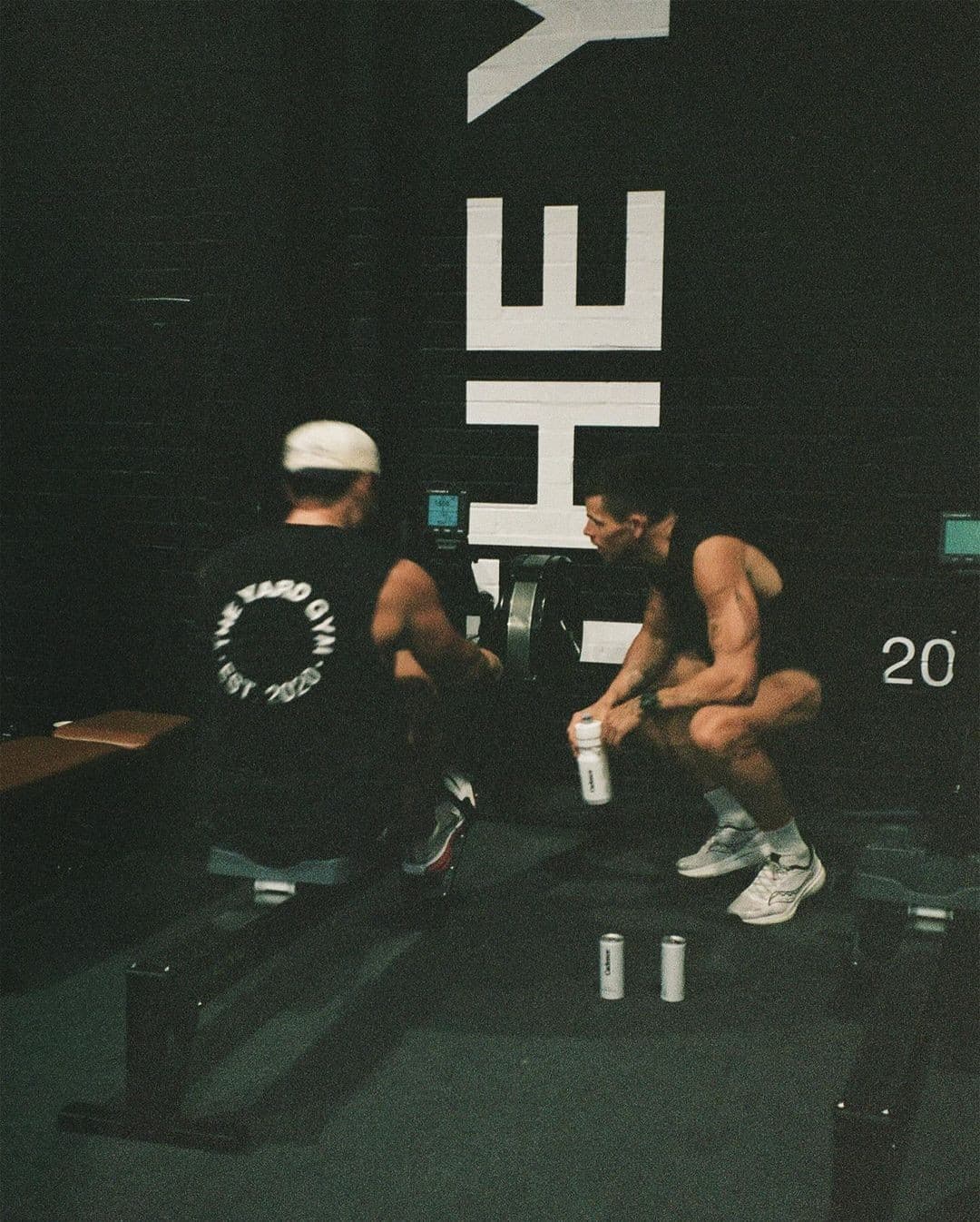 Two athletes talking between sets in a dark gym